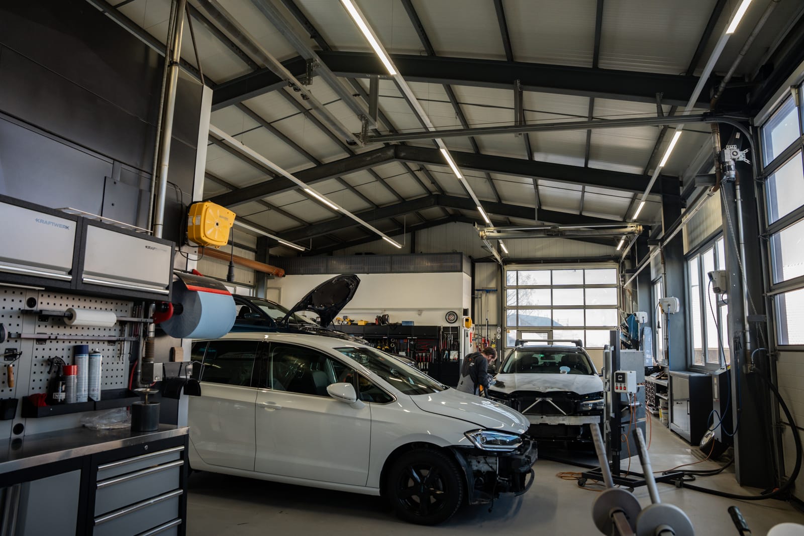 Vue de l’atelier de la Carrosserie du Gibloux avec des véhicules en réparation